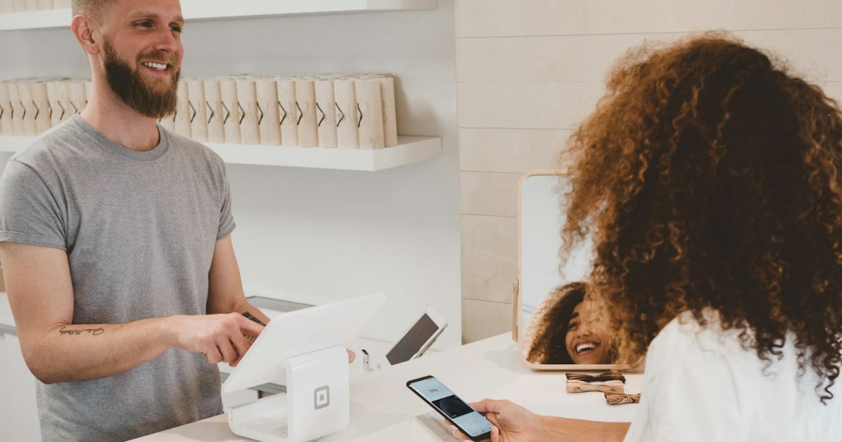 Photo by Clay Banks man in grey crew-neck t-shirt smiling to woman on counter
