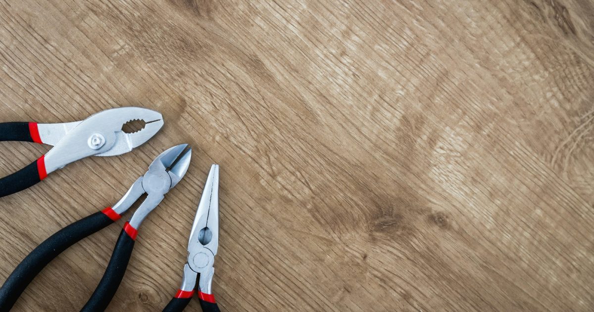 Photo by JESHOOTS.COM three black handled pliers on brown surface